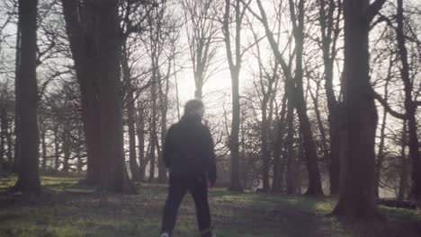 Un-Bosque-Arbolado-Con-Un-Hombre-Caminando-Arriba-Y-Abajo-Por-El-Sendero-Accidentado-En-Una-Tarde-Fría-Y-Brillante-De-Invierno-En-Richmond-Park,-Reino-Unido