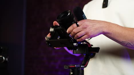 Person-adjust-gimbal-stabilizer-axis-to-balance-digital-camera,-indoor-studio