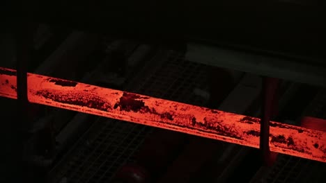 Glowing-hot-steel-bar-in-industrial-setting,-with-dark-background,-focus-on-texture-and-heat
