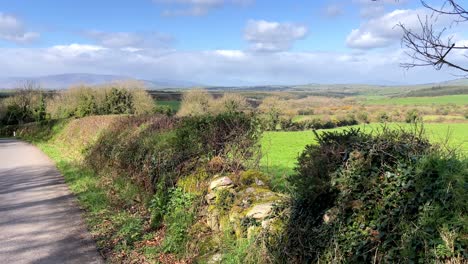 Country-lane-In-Waterford-Ireland-early-Spring-fertile-farmland-with-backdrop-of-Comeragh-Mountains