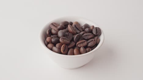 Nahaufnahme-Einer-Hand,-Die-Eine-Weiße-Tasse-Mit-Gerösteten-Kaffeebohnen-Hält