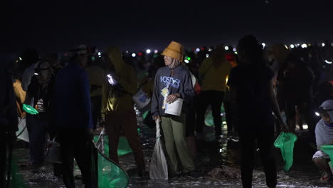 People-At-Sea-Shore-By-Night-With-Flashlights-and-Fishing-Net-Catching-Worm,-Bau-Nyale-Festival-Indonesia