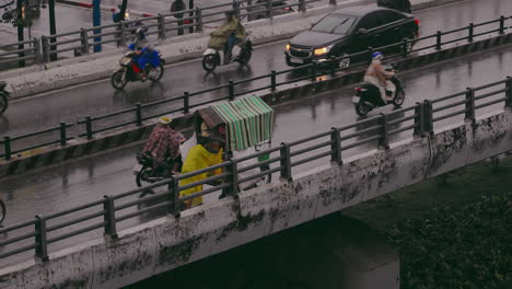 Mann-Schiebt-Sein-Lastendreirad-Im-Regen-über-Die-Brücke