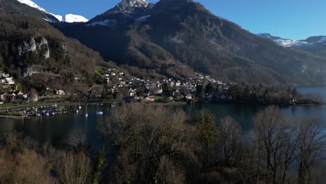 Toma-De-Drone-De-Una-Ciudad-Aislada-Ubicada-Bajo-Una-Montaña-En-Walensee,-Suiza
