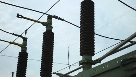 Close-up-of-electrical-insulators-and-cables-against-a-cloudy-sky,-industrial-power-concept