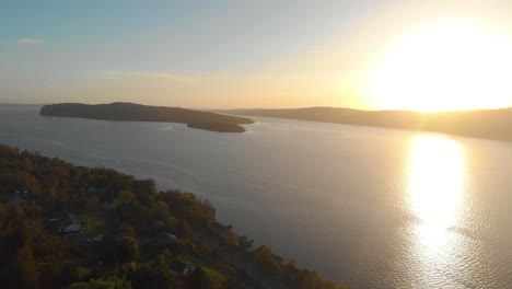 Drone-shot-of-a-stunning-sunset-over-the-water-revealing-some-lake-front-properties-as-the-drone-pulls-back