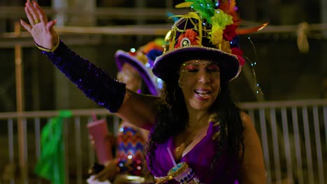Female-carnival-performer-dances-in-middle-of-street-holding-drink-with-shimmering-sequins