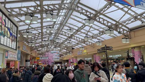 Bustling-indoor-Asian-market-with-colorful-signs,-crowds-shopping