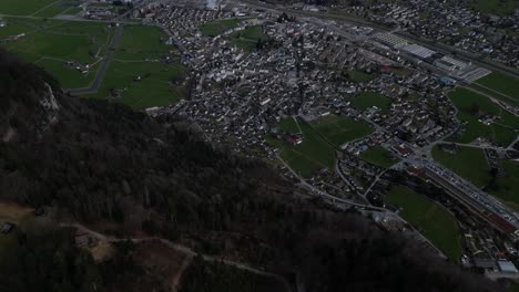 Top-view,-high-altitude-aerial-perspective-of-Glarus,-Switzerland,-showcasing-its-pristine-natural-beauty-and-charming-urban-landscape-nestled-amidst-the-breathtaking-Swiss-Alps