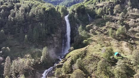Kreisende-Luftaufnahme-Eines-Hohen-Wasserfalls-In-Von-Felsen-Und-Bäumen-Bedeckten-Bergen,-Cascata-La-Froda