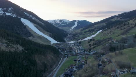 Saalbach-Hinterglemm-ski-resort-in-Austria-during-twilight,-tilting-down-over-the-village,-aerial-view