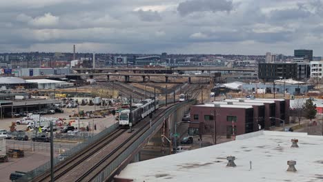 Public-transportation-tramline-rail-system-rises-on-bridge-on-overcast-day-in-Denver-city-outskirts