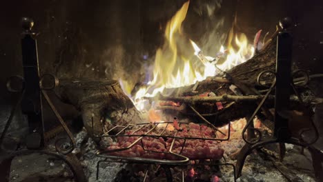 Sausages-cooking-on-fireplace-grill-with-fire-burning-in-background,-Close-up