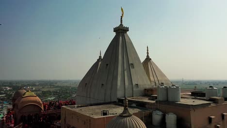 Aerial-drone-view-drone-camera-is-moving-forward-where-from-behind-the-temple-the-drone-is-moving-forward-and-many-people-are-playing-dhuleti-and-many-people-are-watching-from-above