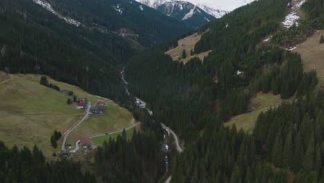 Saalbach-Hinterglemm,-Austrian-ski-resort-nestled-in-alpine-trees,-tilting-up-to-reveal-mountains,-aerial-view