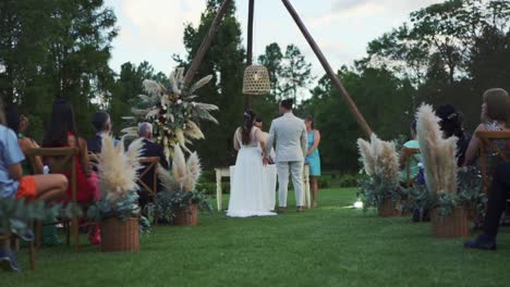 Wedding-ceremony-in-a-field-with-boho-decoration,-the-bride-and-groom-are-standing-in-front-of-the-altar