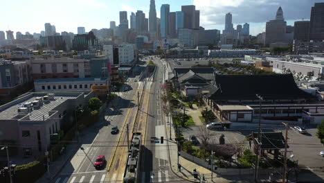 Aerial-view-following-a-tram-moving-toward-the-downtown-of-Los-Angeles,-USA