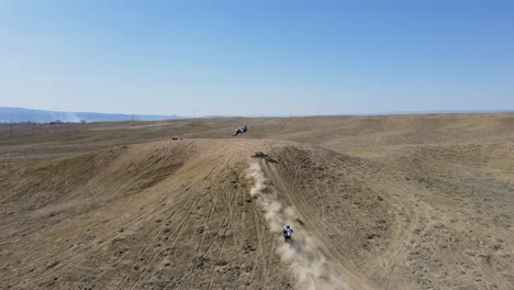 Una-Toma-De-Drones-En-4k-Llena-De-Acción-De-Dos-Pilotos-De-Motocross-Dando-Un-Gran-Salto-En-Una-Colina,-En-El-Terreno-Desértico-Del-área-De-Grand-Valley-OHV,-Ubicada-En-Grand-Junction,-Colorado.