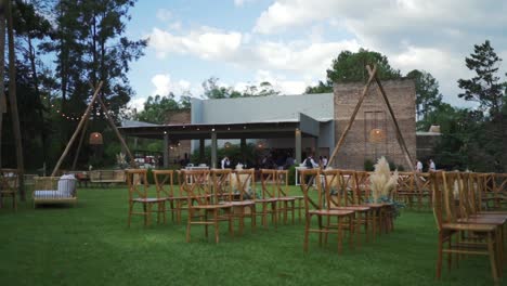 Holzstühle-Für-Die-Hochzeitszeremonie-Auf-Einer-Wiese-Vor-Einem-Veranstaltungsgebäude