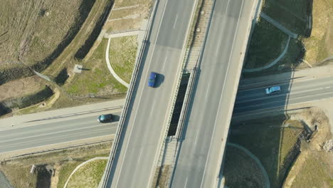 Aerial-view-of-a-bridge-over-a-junction-with-sparse-traffic-and-a-green-car-standing-out