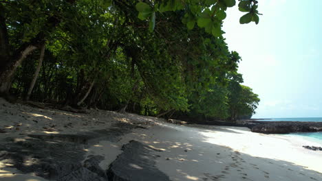 Aerial-view-low-over-white-sand-on-a-beach,-sunny-day-in-Sao-Tome,-Africa