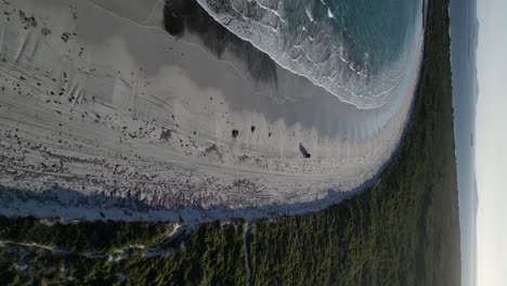 Drone-shot-following-car-on-sandy-beach-of-Wylie-Bay-Beach-at-sunset