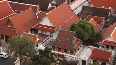 aerial-view-looking-on-red-and-orange-roofs-buddhist-temples-in-the-Rattanakosin-old-town-of-Bangkok,-Thailand