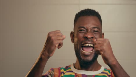 Close-Up-Of-Afro-American-Man-Wearing-Kente-Fabric-Shirt-Expressing-Success