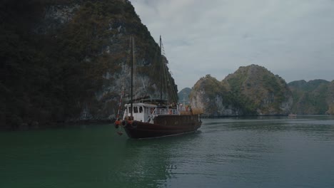 Fishing-Boat-Sailing-Past-Limestone-Cliffs-In-Lan-Ha-Bay,-Vietnam