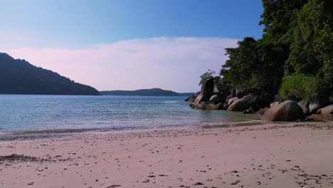 Puesta-De-Sol-En-El-Paraíso-Tropical,-Playa-De-Arena-Junto-A-Un-Frondoso-Bosque,-Agua-Azul-Clara