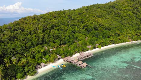 Resort-Con-Cabañas-De-Madera-Y-Techos-De-Paja-A-Lo-Largo-De-La-Exótica-Playa-De-La-Isla-Kri-En-El-Archipiélago-De-Raja-Ampat,-Papúa-Occidental-En-Indonesia