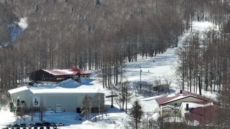 Establishing-shot-of-base-of-ski-slopes,-skiiers-arriving-at-base-of-mountain-where-the-cable-car-bubble-cars-depart-from