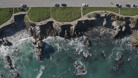 4K-overhead-of-a-beautiful-day-on-the-Monterey-Bay-Recreation-Trail-in-Pacific-Grove-California-with-the-waves-gently-breaking-on-the-shore-and-Ocean-View-Boulevard-at-the-top-of-frame