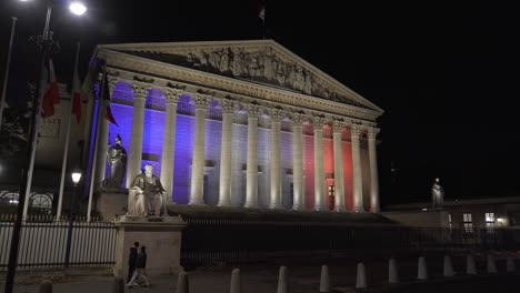 Asamblea-Nacional-Iluminada-De-París-Por-La-Noche-Con-La-Bandera-De-Francia-Ondeando-Los-Colores