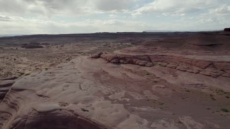 A-spectacular,-reversing-4K-drone-shot-over-the-rugged,-desert-like-terrain-and-unique-rock-formations-of-Whitewash-Sand-Dunes,-a-recreation-area-near-Green-River-and-Moab,-Utah