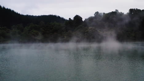 Slow-aerial-over-vapor-rising-from-steamy-geothermal-lake-in-New-Zealand,-North-Island