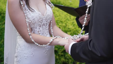 A-bride-and-groom-holding-hands-while-getting-married-in-an-outdoor-religious-ceremony