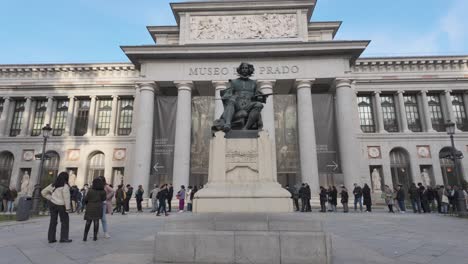 Zu-Fuß-In-Richtung-Museo-Del-Prado-Velazquez-Eingang-Und-Skulptur-An-Einem-Sonnigen-Wintertag-Mit-Menschen-In-Der-Schlange-Stehen