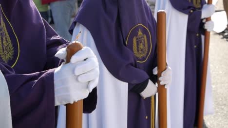 Closeup-of-three-penitent-in-line-formation-dressed-on-traditional-white-and-purple-tunics-ready-to-march