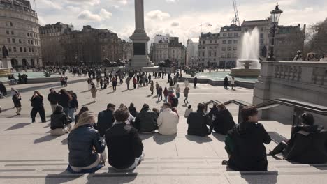 Menschen-Sitzen-Auf-Stufen-Mit-Blick-Auf-Den-Trafalgar-Square-Mit-Nelsonsäule-Und-Brunnen-Im-Hintergrund-An-Einem-Sonnigen-Morgen