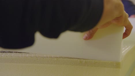 Close-up-of-hands-placing-foam-layer-on-boxspring-in-bed-manufacturing-setting