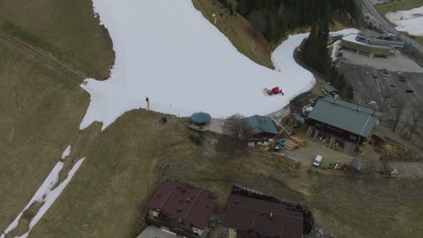 Saalbach-Hinterglemm-ski-resort-with-melting-snow,-tilt-down-shot,-aerial-view