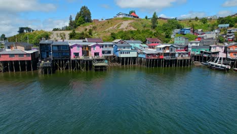 Panning-aerial-orbit-in-the-colorful-stilt-houses-of-Castro,-patrimonial-architecture-of-Chiloe-in-southern-Chile