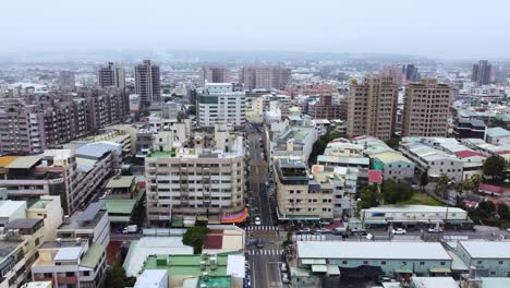 A-dense-cityscape-with-buildings-and-streets-on-overcast-day,-aerial-view