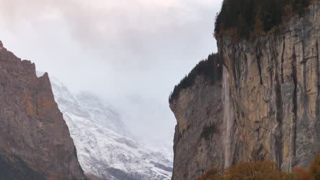 Staubbach-Falls-Lauterbrunnen-Switzerland-Swiss-alpine-valley-village-Jungfrangu-Grindelwalk-Interlaken-Bernese-Alps-sunset-golden-hour-autumn-October-colors-snow-glacier-gigantic-rock-face-pan-down