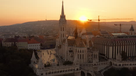 El-Sol-Desaparece-Detrás-De-La-Silueta-De-La-Iglesia-De-Matías,-Proyectando-Un-Tranquilo-Resplandor-Naranja-Sobre-El-Paisaje.