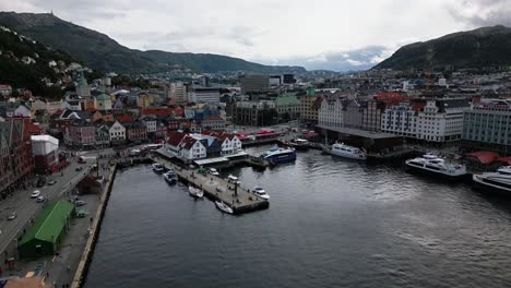 Puerto-En-El-Centro-De-La-Ciudad,-Montañas-Con-Bosque-En-El-Fondo-De-La-Ciudad,-Bergen,-Noruega,-Europa,-Drone