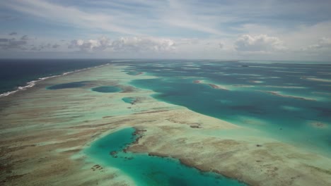 Coral-barrier-in-los-roques,-showcasing-the-stunning-turquoise-waters-and-scattered-islands,-aerial-view