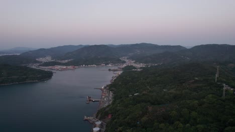 Panoramic-natural-environment-aerial-drone-above-Wakayama-city-Japan-town-dusk-sunset-skylight-at-twilight,-riverside-town