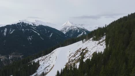 Picos-Cubiertos-De-Nieve-En-La-Estación-De-Esquí-Austriaca-Saalbach-hinterglemm,-Pinos-Que-Salpican-El-Paisaje,-Vista-Aérea